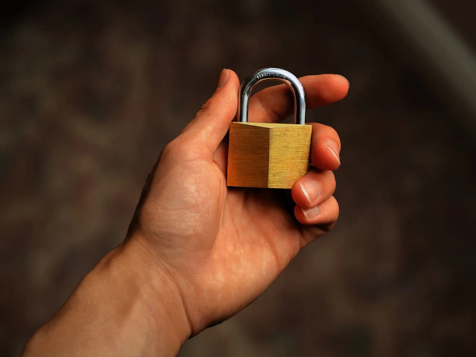 Representational image: a hand holding a brass padlock against a dark background, symbolizing the lock a writer holds on a row until its transaction ends