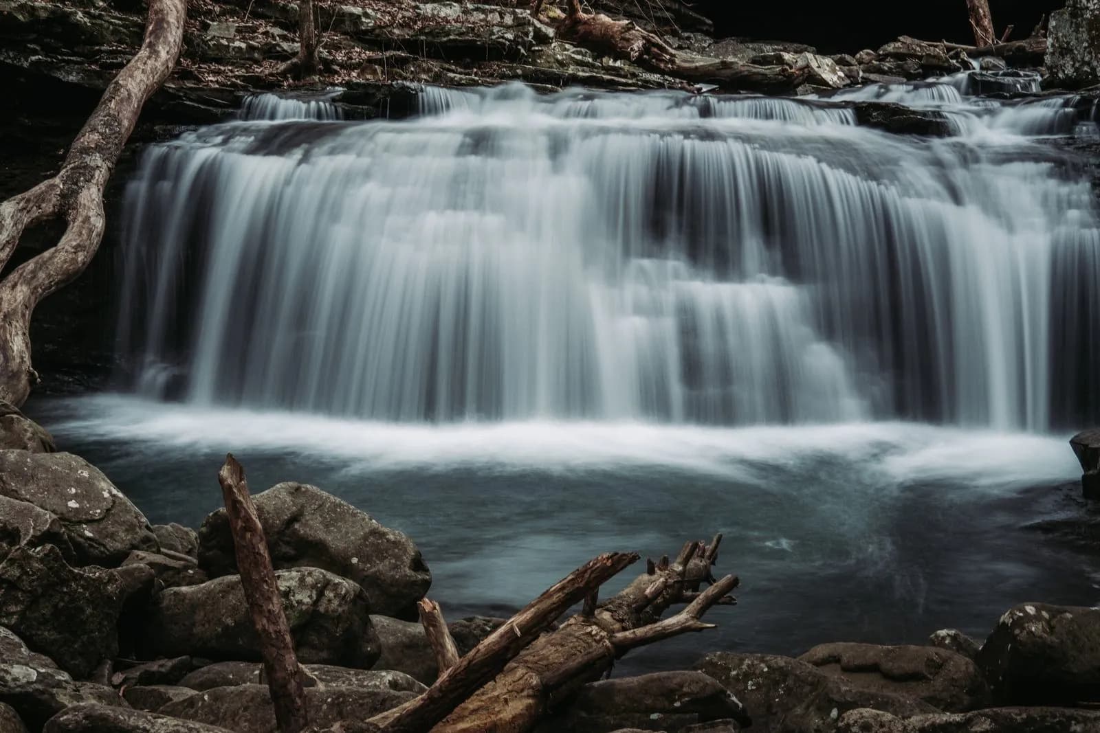 A long-exposure photograph of a waterfall flowing over rocks in a forest