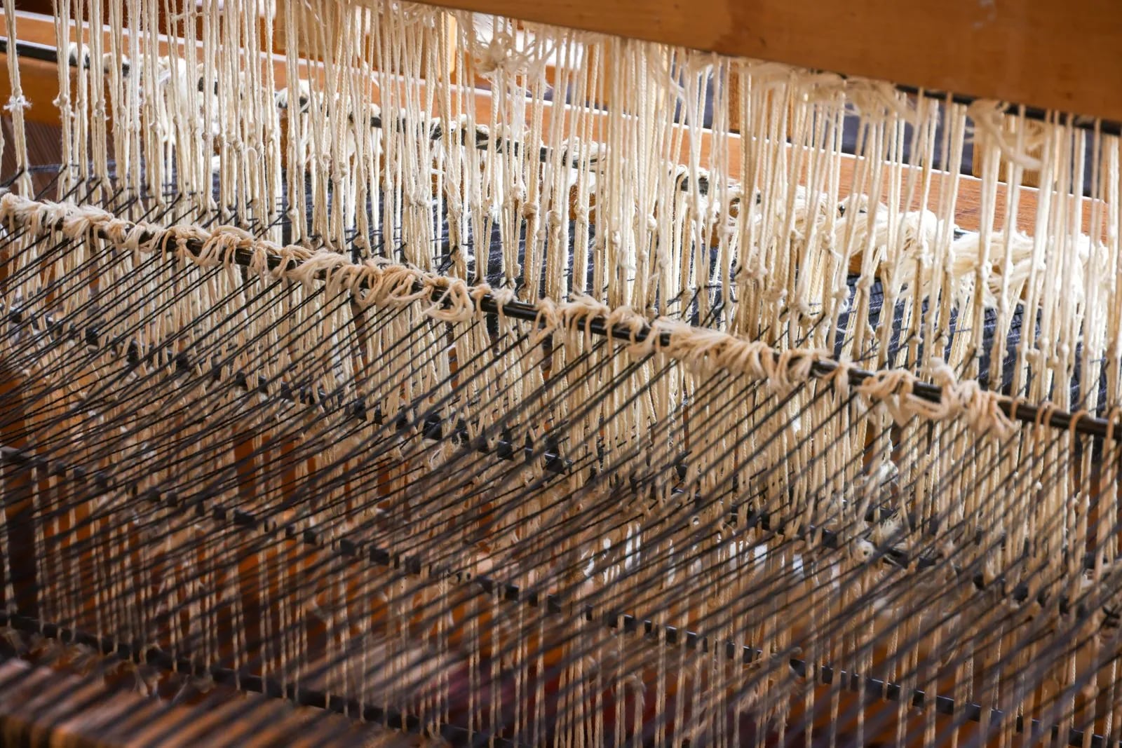 Close-up of a wooden weaving loom with taut threads, weaving fabric