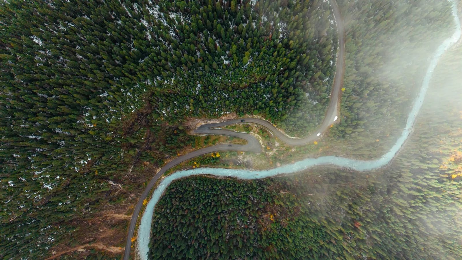 Aerial view of a winding road through a forested valley, like a route through a landscape