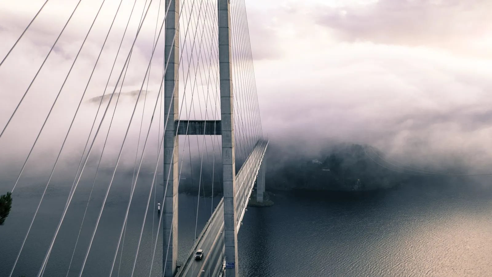 Representational image: a suspension bridge wrapped in fog, symbolizing carefully crossing your production database to a new schema version